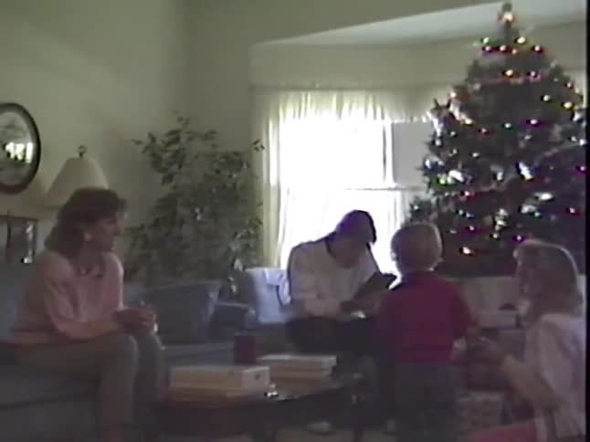 Vintage 1990s home video footage of a family opening presents on Christmas morning in their living room