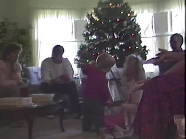 Vintage VHS footage captures a heartwarming family moment as a little boy receives a large present on Christmas morning