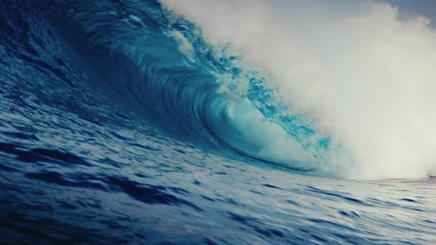 A powerful deep blue ocean wave curls and crashes in dramatic super slow motion