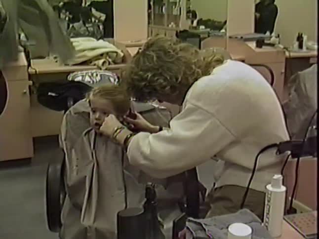 Vintage VHS footage captures a wide-eyed toddler getting his very first haircut at a retro salon