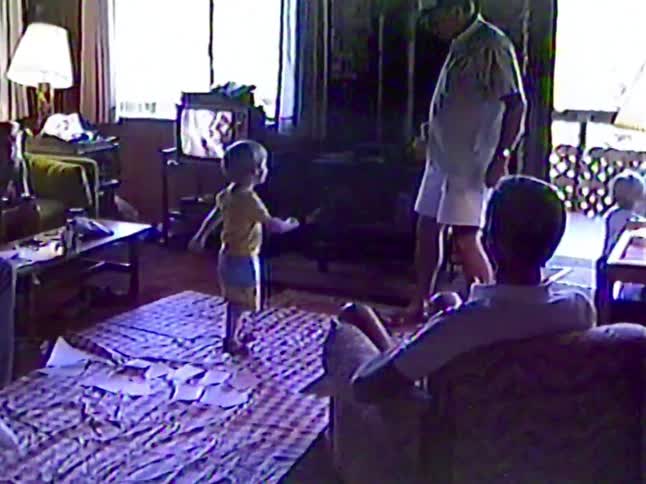 An adorable toddler shows off his dance moves in the living room for his family in this vintage home video