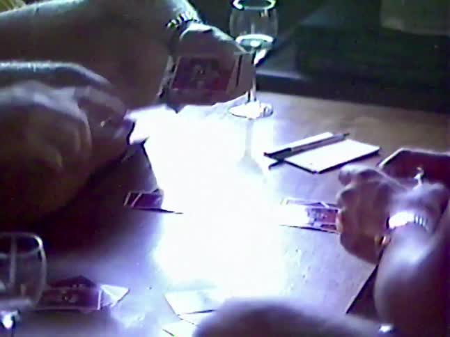 Friends gather in a living room for a friendly game of cards and drinks in this nostalgic 1980s home video