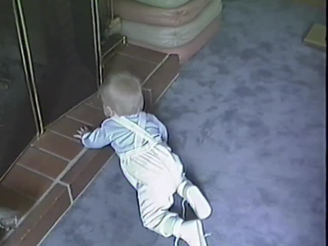 Vintage VHS footage captures a curious baby crawling on the carpet and exploring the fireplace