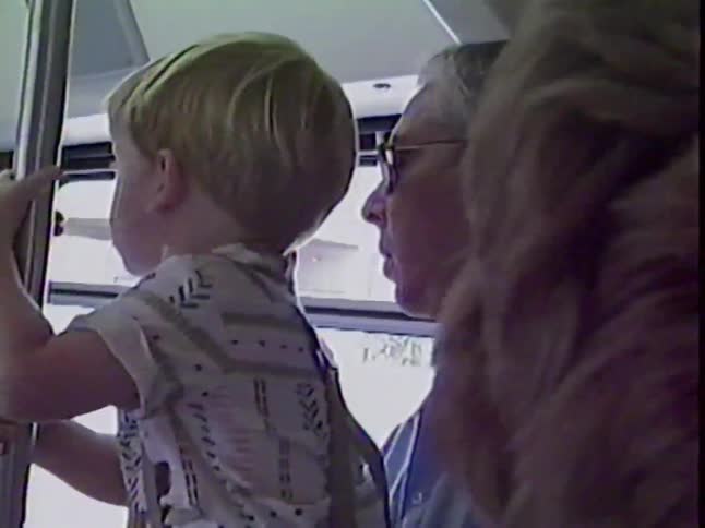 A nostalgic VHS home movie shows a curious young boy and his father riding on a bus together