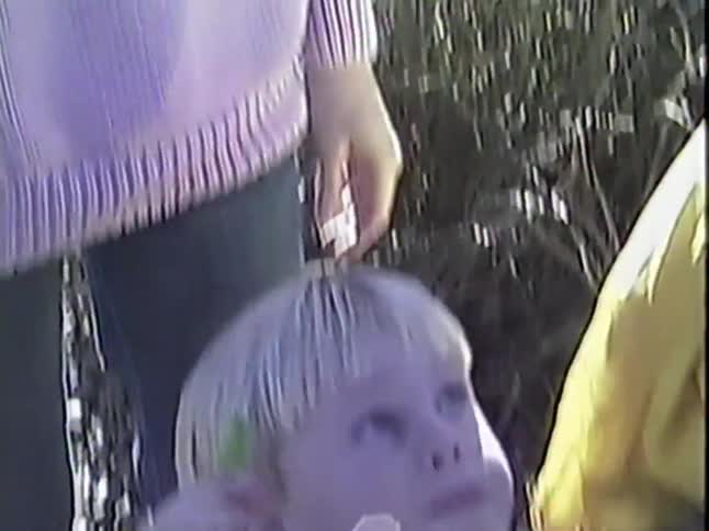 A cheerful little boy in a reindeer sweater and his mother enjoy candy together in a nostalgic VHS clip