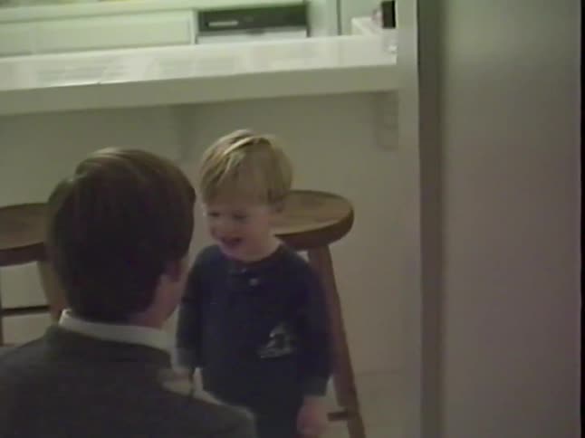 Father plays and makes a toddler laugh in a cozy home kitchen