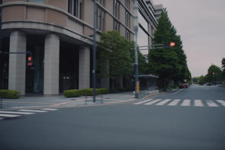 A smooth point-of-view shot travels past modern buildings on a quiet, empty street in a city business district