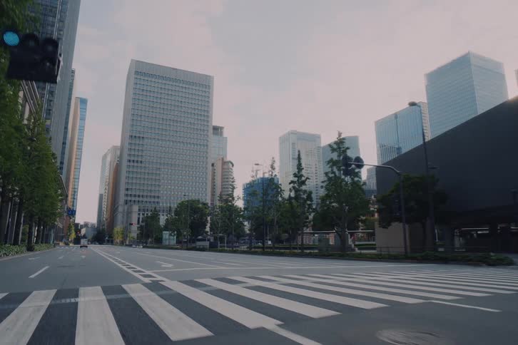 A smooth forward-moving shot through the deserted, sunlit streets of downtown Tokyo, surrounded by modern skyscrapers