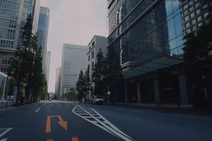 A smooth tracking shot moves down a deserted street in a modern financial district with tall glass skyscrapers