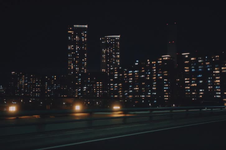 Passenger's point of view driving along a highway with a view of the brightly lit urban cityscape at night