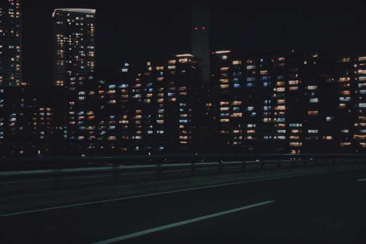 Driving along a city highway at night with a view of the brightly lit skyline