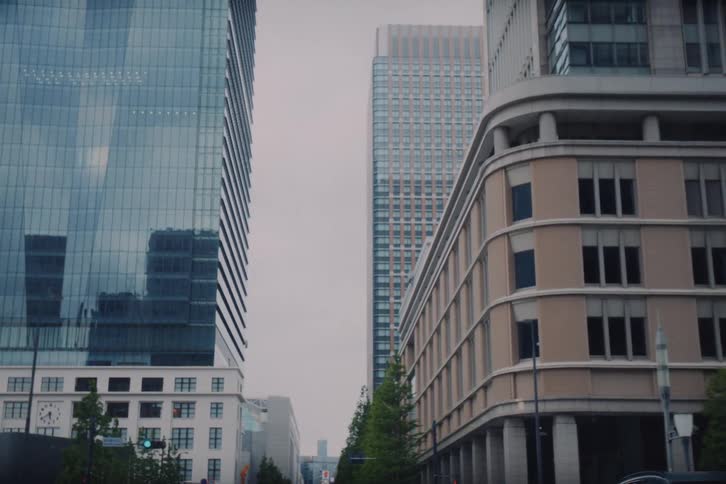 A slow pull-back shot reveals the towering skyscrapers and modern architecture of a city's business district on an overcast day