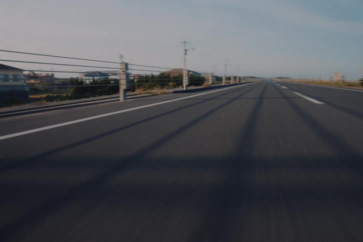A fast-paced, low-angle point-of-view shot driving along an empty coastal highway on a sunny day