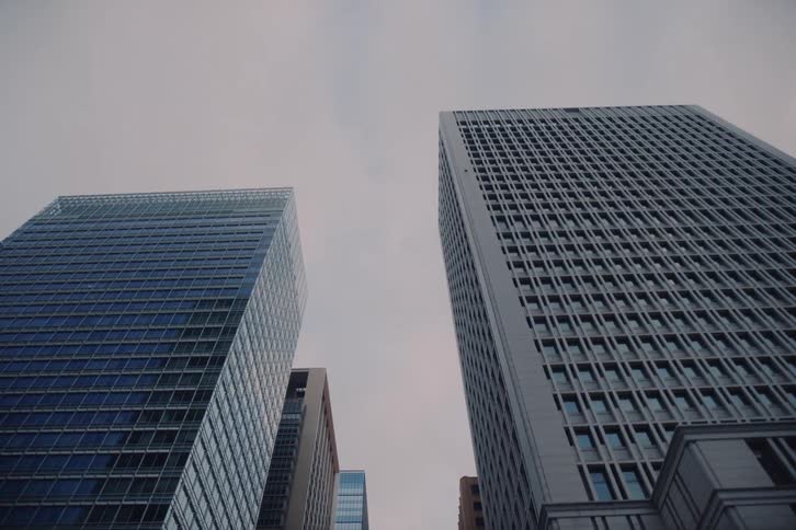 A slow backward tracking shot looking up at the towering skyscrapers of a modern city's financial district