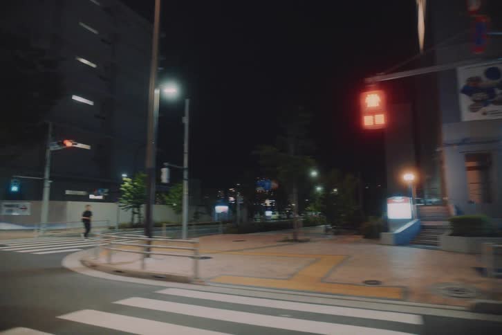 Point-of-view shot driving through the quiet, illuminated streets of a modern city surrounded by towering skyscrapers at night