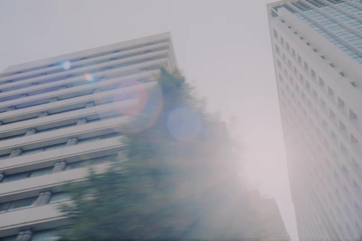A slow-motion, low-angle drive-by shot of modern city skyscrapers and architecture on a bright day