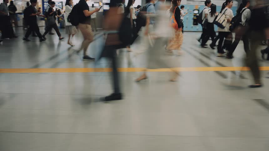 Anonymous commuters create a motion blur effect as they rush through a busy train station in this time-lapse shot