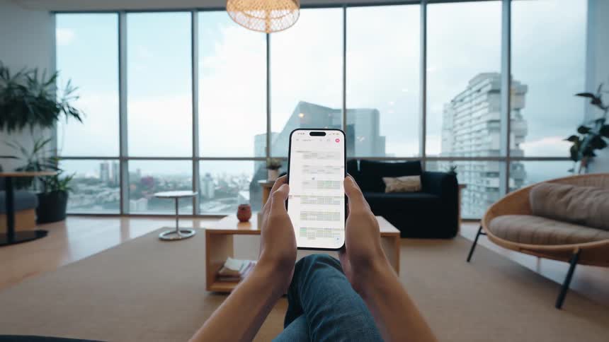 First-person view of hands scrolling through a calendar app on a smartphone in a chic city apartment