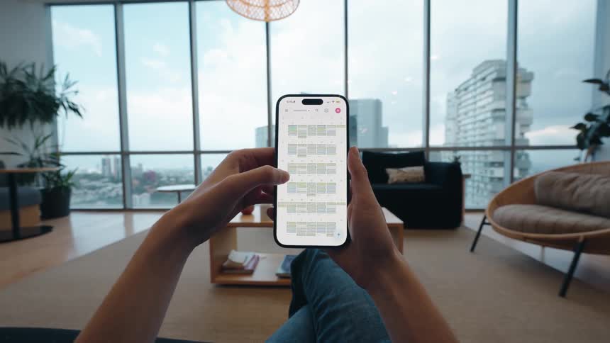 POV of a person relaxing in a modern city apartment while organizing their schedule on a smartphone calendar app