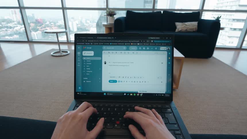 First-person perspective of a person typing an important email on a laptop from their modern high-rise apartment