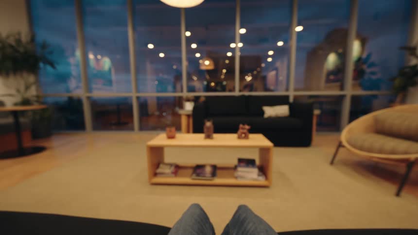 First-person perspective of putting on over-ear headphones in a modern and cozy living room lounge