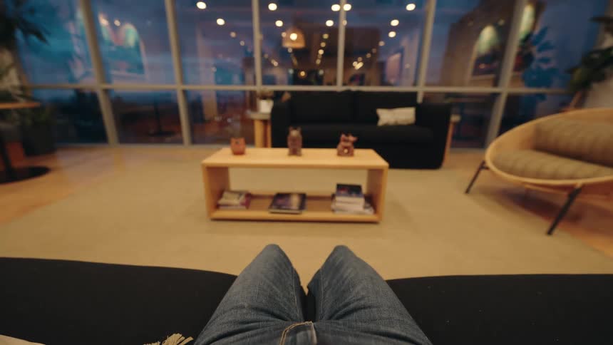 A POV shot of a person putting on over-ear headphones to unwind in a modern lounge at night
