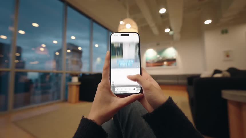First-person view of someone scrolling through a social media feed on their smartphone while relaxing in a modern apartment