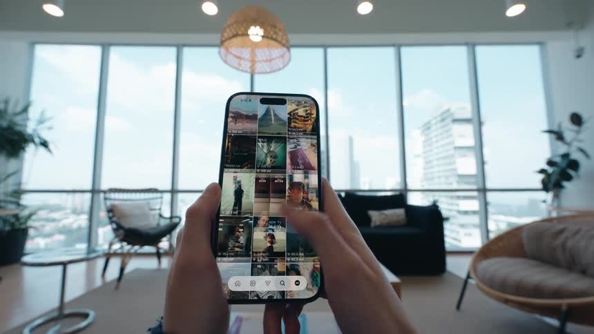 Point-of-view of a person scrolling through a photo and video social media feed on their smartphone in a modern apartment