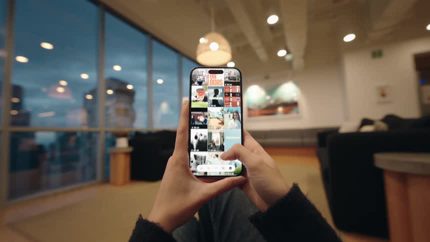 POV of a person endlessly scrolling through a vibrant photo feed on their smartphone in a modern, softly lit room