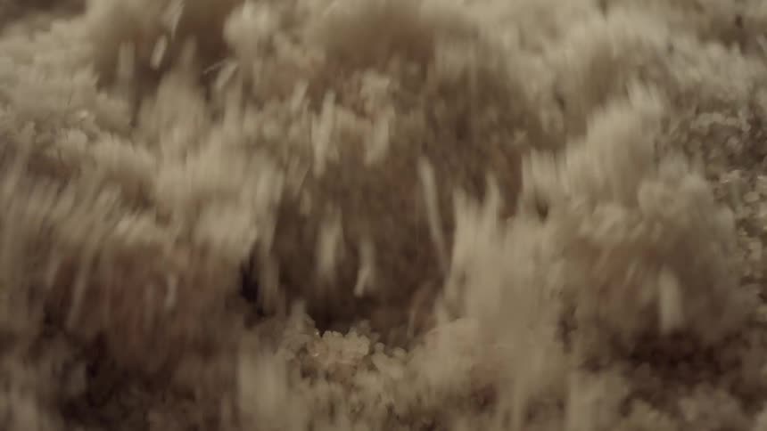 A dynamic extreme close-up of granulated salt being agitated and processed in an industrial machine
