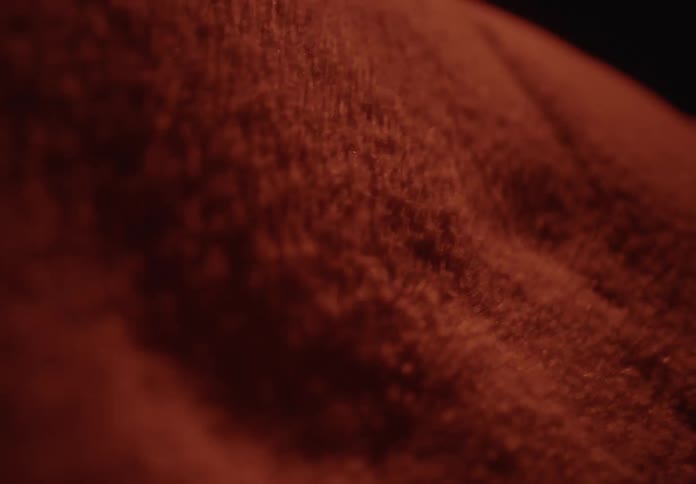 Abstract macro shot of red sand particles vibrating and rippling in slow motion from sound waves