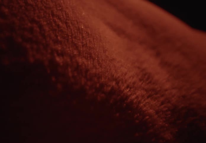 A macro shot shows red spice powder blowing and shifting across a dark, abstract landscape