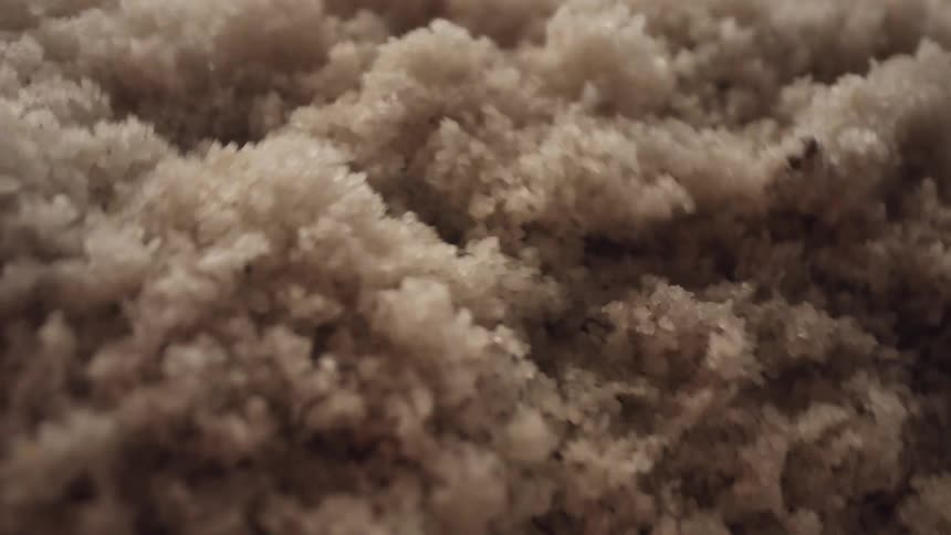An abstract macro view of white salt crystals vibrating and jumping in slow motion
