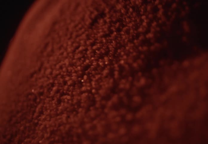 Vibrating red particles dance and form mesmerizing patterns in a close-up Cymatics experiment