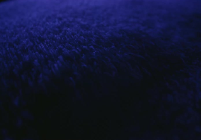 An abstract macro shot of shimmering blue particles swirling and flowing in a dark, mysterious liquid