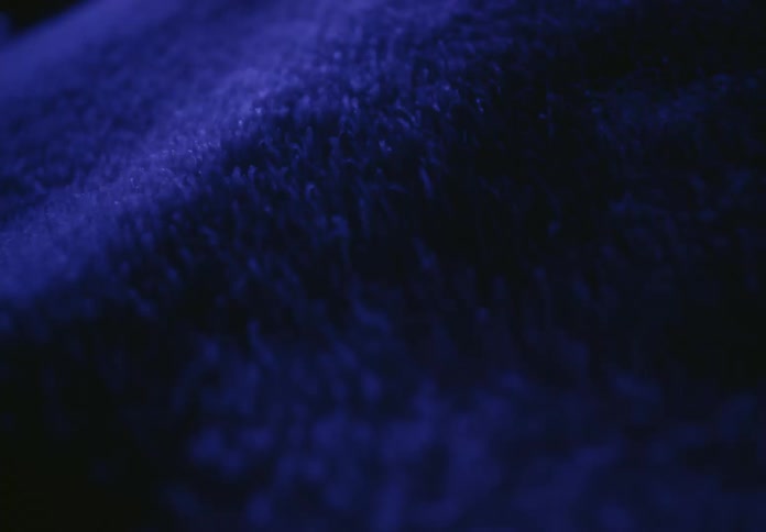 A macro slow-motion shot captures the moving texture of a dark blue, plush, furry fabric
