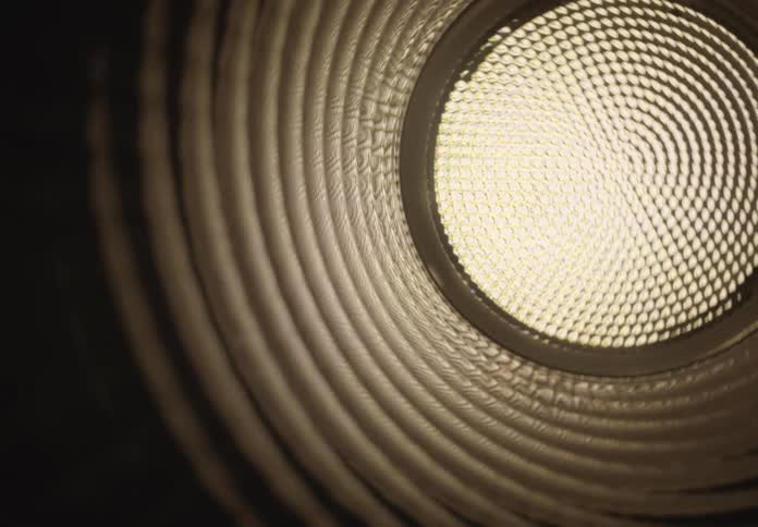 A slow, abstract dolly shot pulling back through a dark, corrugated tunnel towards a bright, circular light