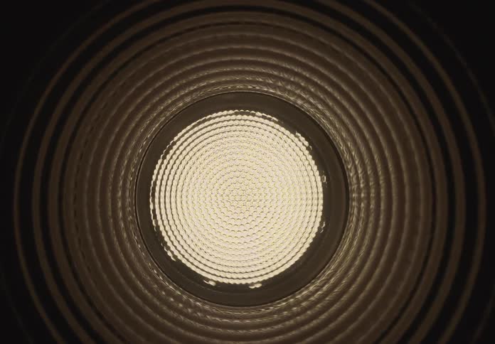 Slowly moving through a dark corrugated pipe towards a bright circular light at the end of the tunnel