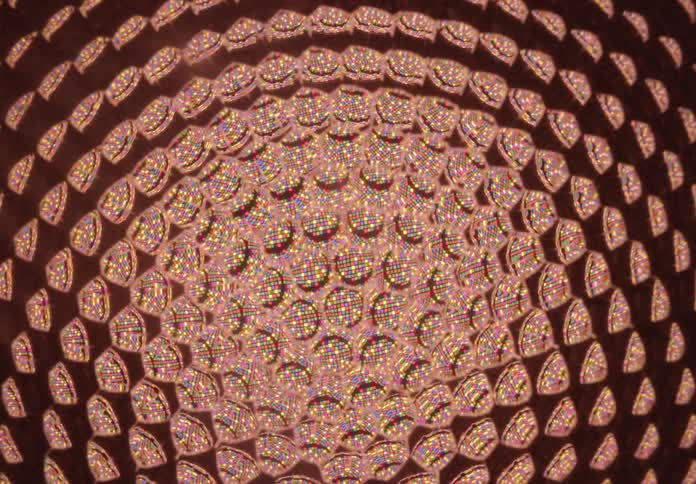 A mesmerizing extreme close-up of a patterned light fixture cycling through a spectrum of colors from cool blue to warm red