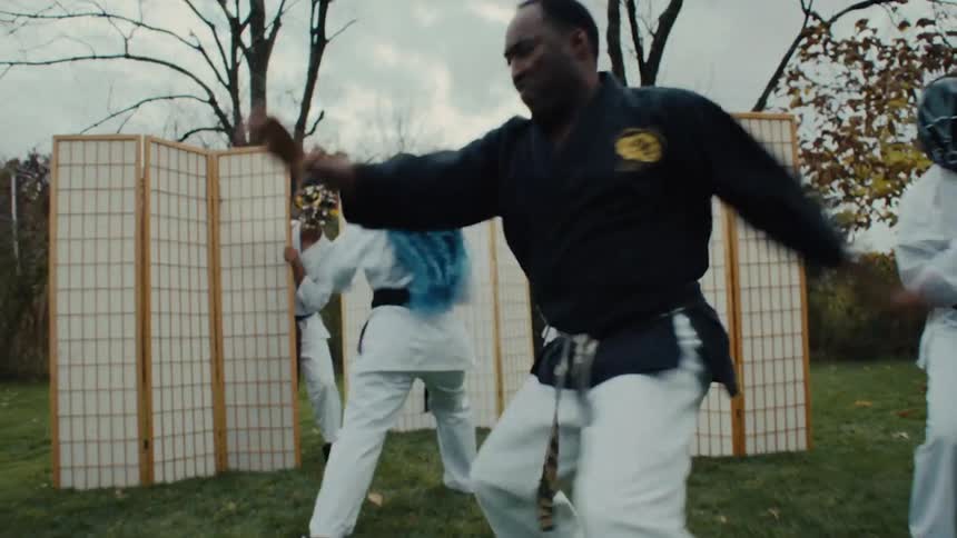 A stylized montage of a karate sensei and his masked students practicing intense martial arts in various surreal indoor and outdoor locations