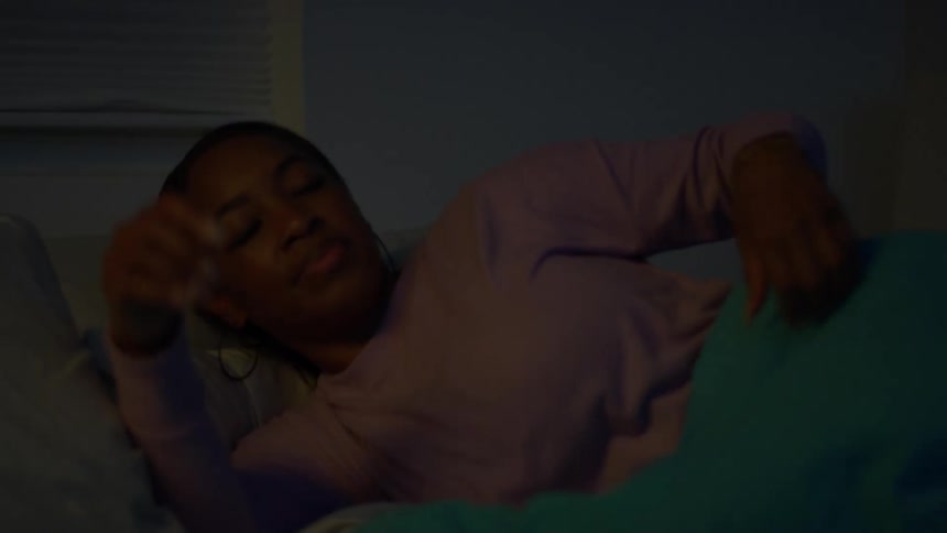 A thoughtful woman turns off her bedside lamp and settles into bed for a peaceful night's sleep