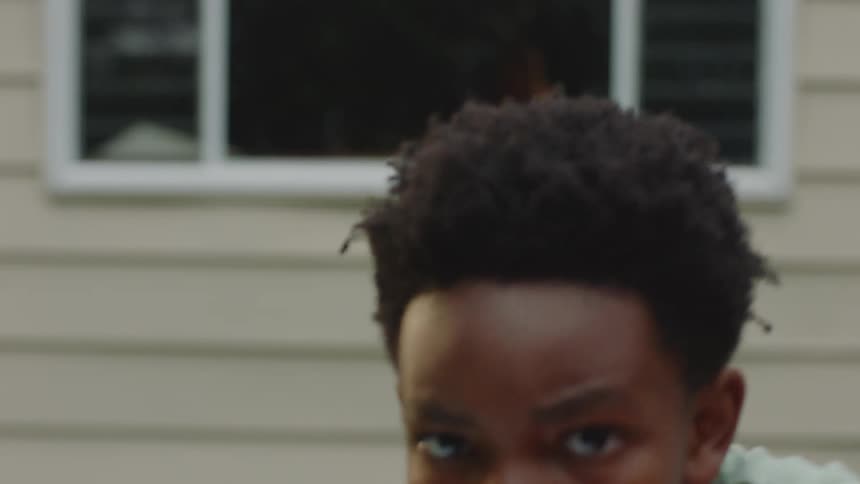 Slow-motion close-up of a determined young boy in boxing gloves punching towards the camera