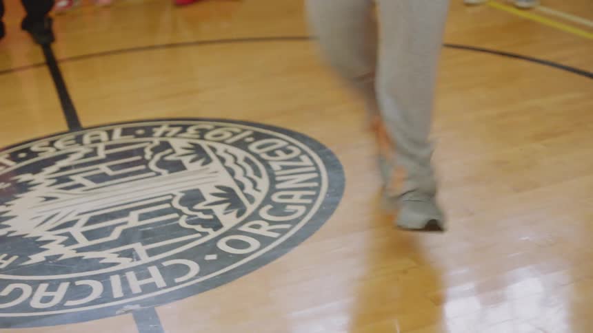 A talented dancer showcases his fast and intricate footwork on a gymnasium floor for an enthusiastic crowd