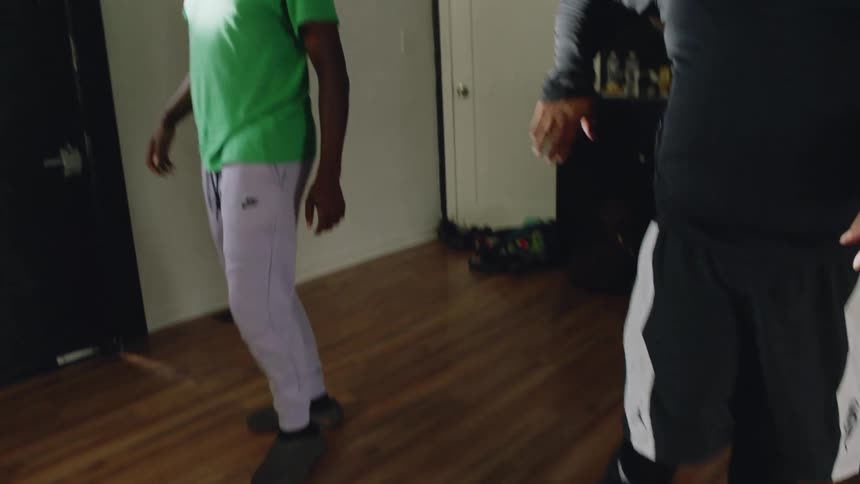Slow-motion view of three friends dancing hip-hop in a living room as the camera tilts down to their feet