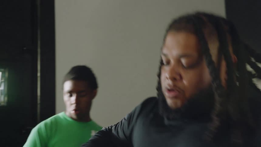 Two determined men catch their breath in slow motion after a vigorous workout in a dimly lit gym