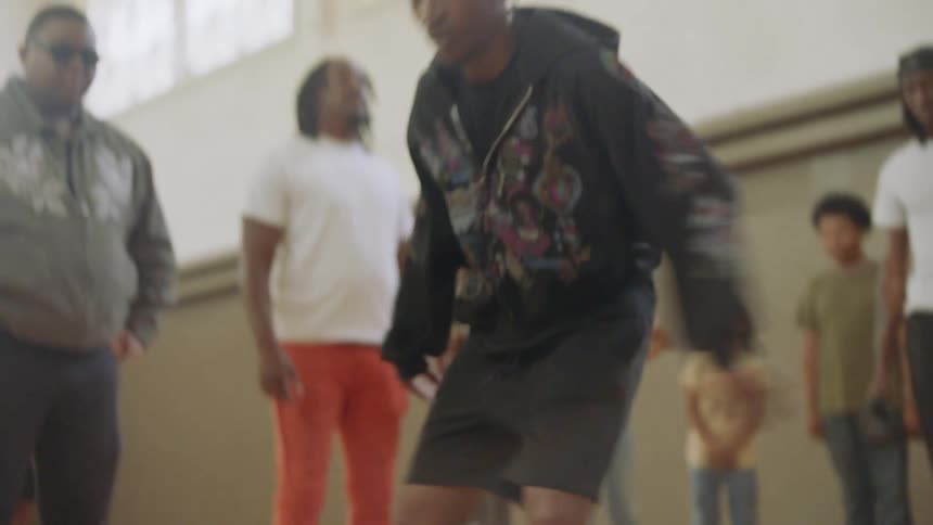A young man showcases incredible Chicago juke and footwork skills for an audience on an indoor basketball court