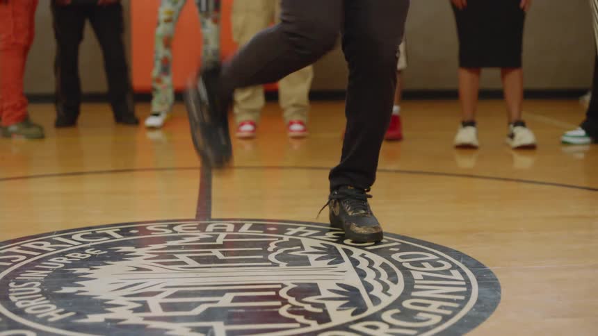 A dancer shows off impressive and energetic footwork on a Chicago Park District seal in the middle of a basketball court
