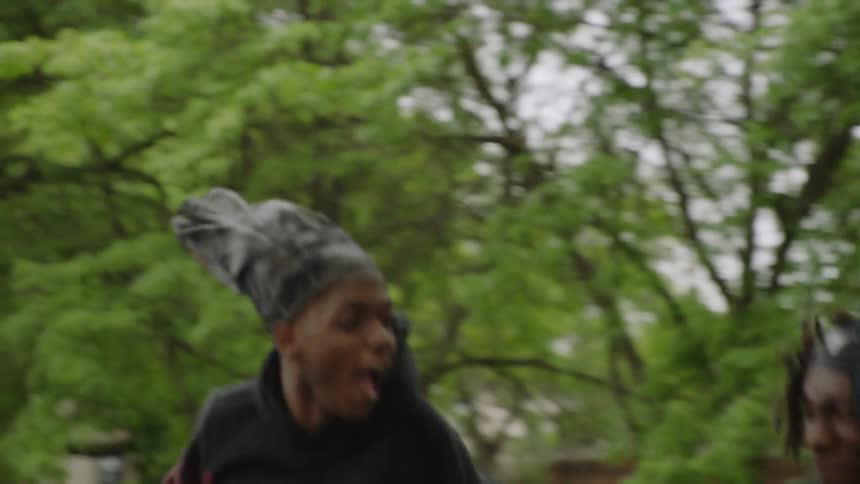 A basketball player jumps high in the air to grab a rebound in slow motion on an outdoor court
