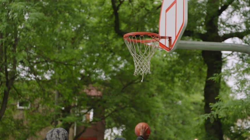 A basketball bounces off the rim in slow motion as players on the court below get ready to rebound