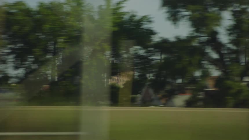 A fast-paced point-of-view shot from a moving vehicle captures the blur of passing trees and traffic on a highway